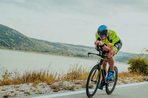 Full length portrait of an active triathlete in sportswear and with a protective helmet riding a bicycle. Selective focus photo