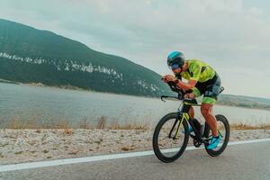 Full length portrait of an active triathlete in sportswear and with a protective helmet riding a bicycle. Selective focus photo