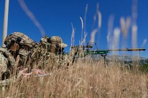 Sniper soldier assisted by an assistant to observe the area to be targeted with modern warfare tactical virtual reality goggles aerial drone military technology photo