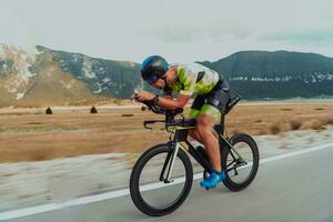 Full length portrait of an active triathlete in sportswear and with a protective helmet riding a bicycle. Selective focus photo