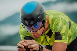 Close up photo of an active triathlete in sportswear and with a protective helmet riding a bicycle. Selective focus