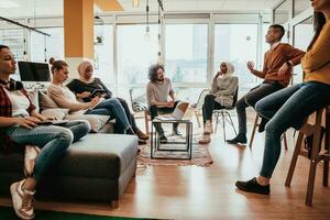 Young designer giving some new ideas about project to his partners in conference room. Business people discussing over new business project in office. photo