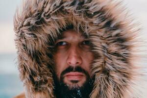 Headshot photo of a man in a cold snowy area wearing a thick brown winter jacket and gloves. Life in cold regions of the country.