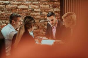 Happy businesspeople smiling cheerfully during a meeting in a coffee shop. Group of successful business professionals working as a team in a multicultural workplace. photo