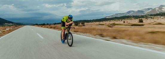 Full length portrait of an active triathlete in sportswear and with a protective helmet riding a bicycle. Selective focus photo