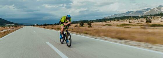 lleno longitud retrato de un activo triatleta en ropa de deporte y con un protector casco montando un bicicleta. selectivo atención foto