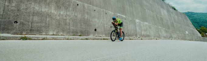 Full length portrait of an active triathlete in sportswear and with a protective helmet riding a bicycle. Selective focus photo