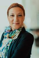 Portrait of business senior woman with crossed arms standing in modern corporation. Selective focus photo