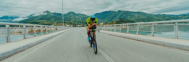 lleno longitud retrato de un activo triatleta en ropa de deporte y con un protector casco montando un bicicleta. selectivo atención foto