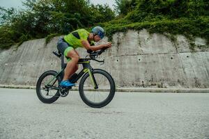 Full length portrait of an active triathlete in sportswear and with a protective helmet riding a bicycle. Selective focus photo