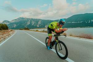 Full length portrait of an active triathlete in sportswear and with a protective helmet riding a bicycle. Selective focus photo