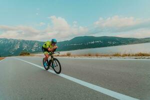 lleno longitud retrato de un activo triatleta en ropa de deporte y con un protector casco montando un bicicleta. selectivo atención foto