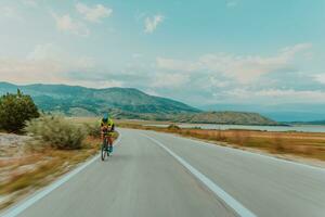 Full length portrait of an active triathlete in sportswear and with a protective helmet riding a bicycle. Selective focus photo