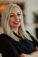 Portrait of business senior woman with crossed arms standing in modern corporation. Selective focus photo