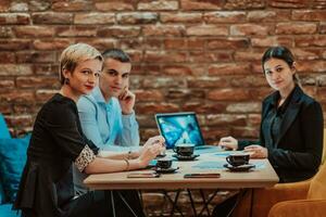 Happy businesspeople smiling cheerfully during a meeting in a coffee shop. Group of successful business professionals working as a team in a multicultural workplace. photo