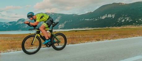 Full length portrait of an active triathlete in sportswear and with a protective helmet riding a bicycle. Selective focus photo