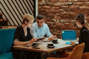 Happy businesspeople smiling cheerfully during a meeting in a coffee shop. Group of successful business professionals working as a team in a multicultural workplace. photo