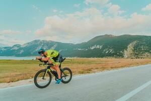 Full length portrait of an active triathlete in sportswear and with a protective helmet riding a bicycle. Selective focus photo