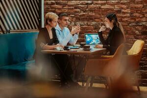 Happy businesspeople smiling cheerfully during a meeting in a coffee shop. Group of successful business professionals working as a team in a multicultural workplace. photo