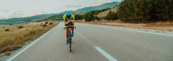 Full length portrait of an active triathlete in sportswear and with a protective helmet riding a bicycle. Selective focus photo