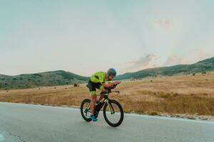 Full length portrait of an active triathlete in sportswear and with a protective helmet riding a bicycle. Selective focus photo