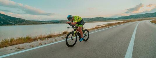 Full length portrait of an active triathlete in sportswear and with a protective helmet riding a bicycle. Selective focus photo