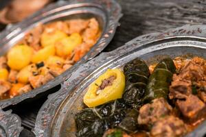 Eid Mubarak Traditional Ramadan Iftar dinner. Assorted tasty food in authentic rustic dishes on wooden blue background. Turkish Bosnian food meat kebab, pita, Sarma, klepe, sogan dolma. photo