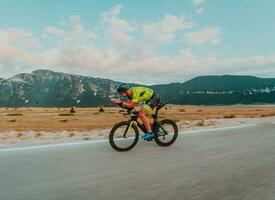 Full length portrait of an active triathlete in sportswear and with a protective helmet riding a bicycle. Selective focus photo