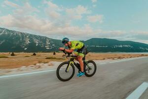 Full length portrait of an active triathlete in sportswear and with a protective helmet riding a bicycle. Selective focus photo