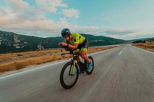 Full length portrait of an active triathlete in sportswear and with a protective helmet riding a bicycle. Selective focus photo