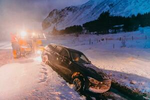 The roadside assistance service pulling the car out of the canal. An incident on a frozen Scandinavian road. photo