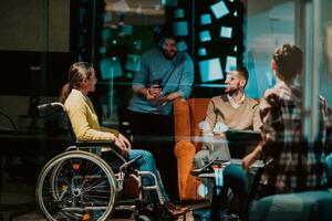 Businesswoman in wheelchair having business meeting with team at modern office. A group of young freelancers agree on new online business projects photo