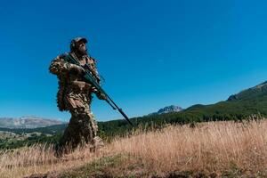 Ejército soldado participación un francotirador rifle con alcance y caminando en el bosque. guerra, ejército, tecnología y personas concepto. foto