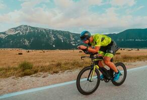 Full length portrait of an active triathlete in sportswear and with a protective helmet riding a bicycle. Selective focus photo