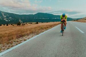 Full length portrait of an active triathlete in sportswear and with a protective helmet riding a bicycle. Selective focus photo