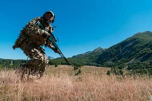 Army soldier holding a sniper rifle with scope and walking in the forest. war, army, technology and people concept. photo