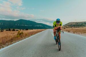 Full length portrait of an active triathlete in sportswear and with a protective helmet riding a bicycle. Selective focus photo