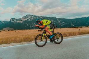 Full length portrait of an active triathlete in sportswear and with a protective helmet riding a bicycle. Selective focus photo