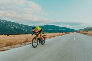 Full length portrait of an active triathlete in sportswear and with a protective helmet riding a bicycle. Selective focus photo