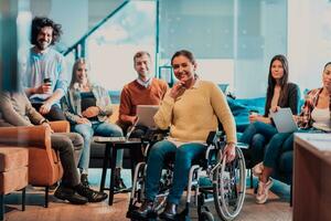 mujer de negocios en silla de ruedas teniendo negocio reunión con equipo a moderno oficina. un grupo de joven autónomos de acuerdo en nuevo en línea negocio proyectos foto