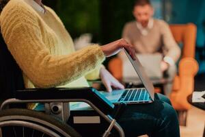 Businesswoman in wheelchair having business meeting with team at modern office. A group of young freelancers agree on new online business projects photo