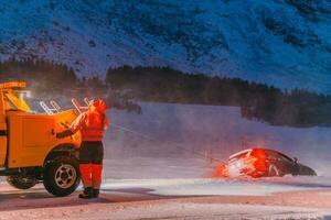 The roadside assistance service pulling the car out of the canal. An incident on a frozen Scandinavian road. photo