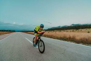 Full length portrait of an active triathlete in sportswear and with a protective helmet riding a bicycle. Selective focus photo