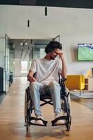 A sad businessman in a wheelchair occupies a hallway within a modern startup coworking center, embodying inclusivity and determination in the business environment photo