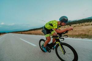 Full length portrait of an active triathlete in sportswear and with a protective helmet riding a bicycle. Selective focus photo