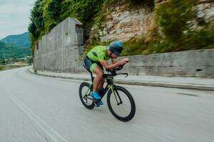 Full length portrait of an active triathlete in sportswear and with a protective helmet riding a bicycle. Selective focus photo