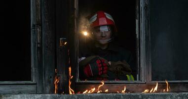 Firefighter hero carrying baby girl out from burning building area from fire incident. Rescue people from dangerous place photo