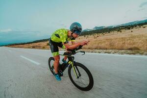 Full length portrait of an active triathlete in sportswear and with a protective helmet riding a bicycle. Selective focus photo