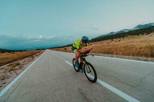 Full length portrait of an active triathlete in sportswear and with a protective helmet riding a bicycle. Selective focus photo