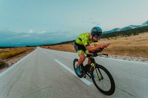 Full length portrait of an active triathlete in sportswear and with a protective helmet riding a bicycle. Selective focus photo